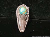 Front view of the ring showing the turquoise stone and silver design against black background.