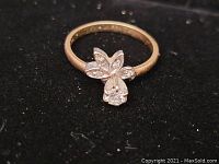 Close-up of the 14K gold ring with floral diamond detail on a black background.