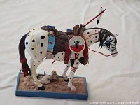 Front-right angled view of the painted horse figurine showing painted details, shield on the side, and spear with feathers.