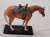 Side view of the first painted pony horse figurine with detailed western saddle and rope, mounted on black base.