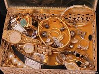Open jewelry box with assorted costume jewelry including watches, bangles, rings, earrings, and faux pearl necklace