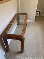 Side angle view of wooden side table with clear glass top showing rounded edges and natural wood finish.