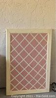 Rectangular distressed white wooden framed memory board with pink and white pattern fabric backing and white diagonal ribbon forming lattice for holding items.