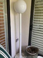 Front view of white globe floor lamp showing full height and details of base and spherical shade