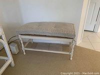 Upholstered wooden bench with patterned fabric seat and turned legs under natural indoor lighting.