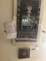 Front view of two acrylic encased tapestries hanging on wall with Certificate of Authenticity attached to the larger tapestry.