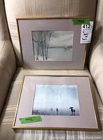 Two framed watercolor on silk prints displayed side by side on a chair