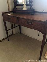 Full view of the vintage wood desk with two drawers and metal drop handles.