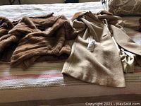 Wide view of the vintage coat laid out next to fur shawls on a bed, showing the coat's color and fur items around.
