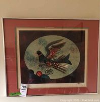 Framed signed art print showing a stylized bird with mechanical wheels, red and blue abstract patterns, and a silver frame with reddish-brown matting.