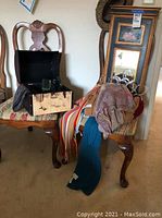 Chest with open top showing glassware inside and several scarves draped over a chair.