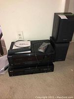 Sony TEAC stereo components and pair of Sony speakers stacked on floor including a COBY DVD player, remote controls, and instruction manual.