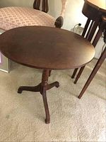 Oval wooden tilt top table showing the full table and tripod base.
