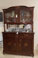 Front view of vintage wooden breakfront and buffet with glass doors and ornate carvings.