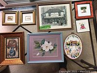 Full view of the eight pieces arranged on carpeted floor showing variety of media and framing.