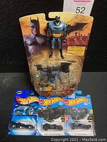 Full lot of 5 Batman collectibles including 1 loose 1998 figure, 1 sealed Roto Blade 2005 Batman figure in packaging, and 3 sealed Hot Wheels die-cast Batmobiles.
