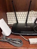 TP-Link wireless router with two antennas, white vintage Macintosh keyboard, white TP-Link power adapter and black power cords