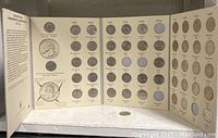 Open view of the archival book with multiple coin slots displayed, some filled with quarters, others empty.