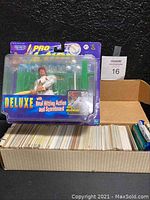 Photo showing box filled with hundreds of baseball trading cards and the Mark McGwire action figure in its original packaging on top of the box