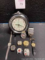 One photo showing the Sterling & Noble alarm clock and 9 watches laid out on a surface, including a Mickey Mouse watch and a smaller keychain watch.