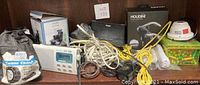 Shelf with mixed items including Houdini lever screw box, Cable Chain bag, Sony radio, security camera, and tangled cables.