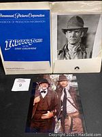 Blue production handbook for Indiana Jones and the Last Crusade with two 8x10 photos; one black-and-white of Harrison Ford and one color photo of Harrison Ford and Sean Connery together.