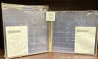 Two IKEA LEKMAN square holder shelves in purple sealed in original plastic packaging with product information label visible.