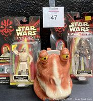 Photo of Jar Jar Binks coffee mug and two Star Wars Episode 1 action figures in packaging: Qui-Gon Jinn and Captain Tarpals.