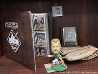 Main shot showing the card album, bobblehead, Lou Gehrig plaque, and baseball glove together on a shelf.