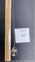 Full length of the necklace beside a ruler showing chain measurement and oval Snoopy pendant close-up