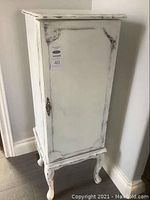 Front view of standing jewelry cabinet showing single door and cabriole legs