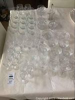 Full overview of the glass and crystal barware set, showing multiple glasses, candy dishes, and cream and sugar set on tablecloth.