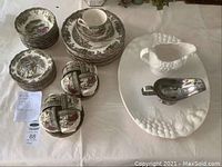 Overview of dinnerware set with plates, bowls, cups, saucers, turkey platter, gravy boat and metal sauce dish.
