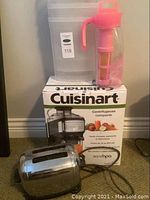 Photo showing Cuisinart juice extractor box with vintage toaster in front, and translucent storage bins and pink water jug behind