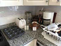Countertop with Philips coffee maker, two-slice white toaster, glass pitcher, salt and pepper shakers, teapot, knife block, and some utensils.
