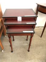 Front angle view of all three nesting tables stacked by size showing the smallest at the bottom, largest on top.