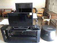 Sony TV and RCA monitor on black TV stand, with side black ottoman visible