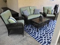 Full set on patio: loveseat center, two chairs, coffee table on rug