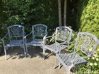 Four cast metal garden chairs arranged outdoors on a patio
