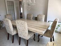 Full view of marble table top, pedestal base, and six chairs arranged in dining room