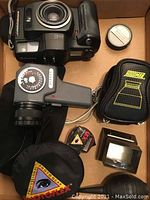 Top view showing camera body, light meter, lens cap, two pouches, slide viewer hood, two slide loops and small reflector ring