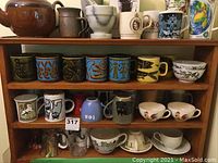 Wooden shelf displaying teapot, mortar, pestle and multiple mugs
