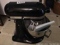 Front right angle of black tilt-head mixer with bowl and flat beater