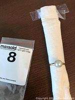 Ring on white wrapped display tube with MaxSold lot tag visible