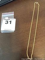 Full length view of 18" gold heart link chain alongside auction tag