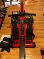 Front view of rowing machine showing handlebar, digital monitor, footrests, and water tank