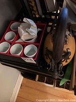 Photo showing large teapot with serpent handle, single serve teapot and five white china cups in red box.