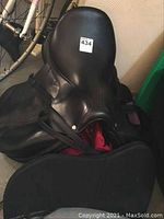 Front and side view of black CWD English saddle on wooden chest