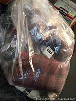 Clear bag of multiple burgundy yarn balls with lot sticker visible