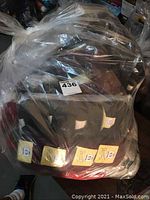 Clear plastic bag filled with multiple yarn skeins visible, some with yellow Lana Gatto Feeling labels, various colors including reds and greys.
